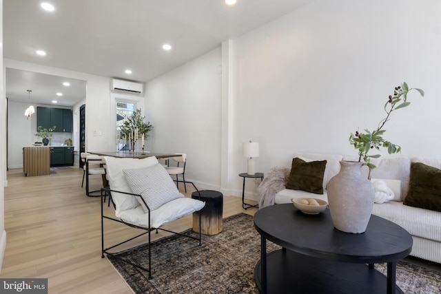 living area with a wall mounted AC, a chandelier, and light wood-type flooring