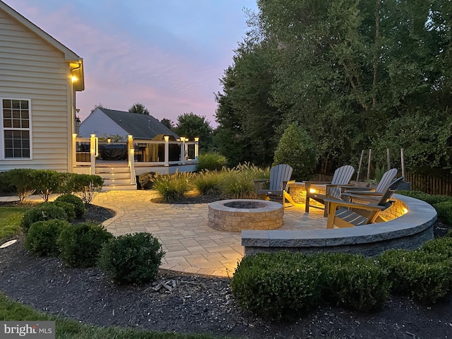 patio terrace at dusk with a fire pit and a deck