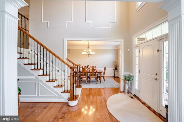 entryway with a notable chandelier, crown molding, and light hardwood / wood-style flooring