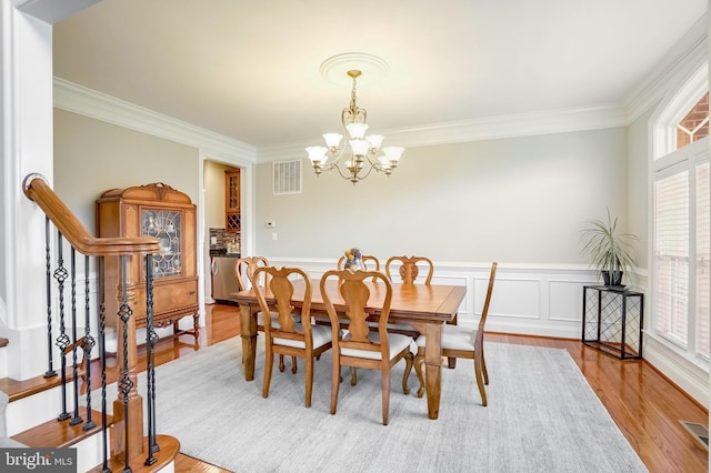 dining space with light hardwood / wood-style flooring, a notable chandelier, and crown molding