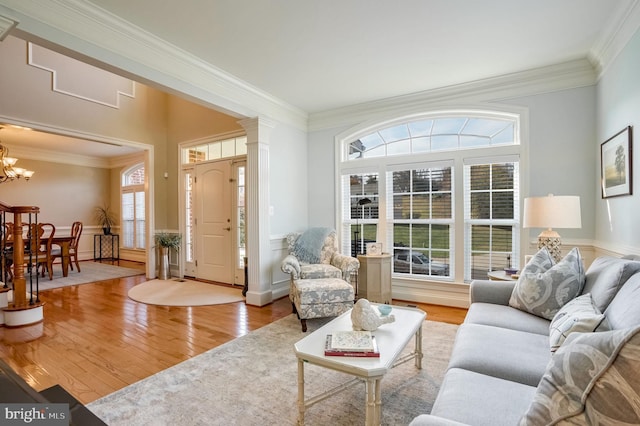 living room featuring light hardwood / wood-style flooring, a wealth of natural light, crown molding, and a notable chandelier