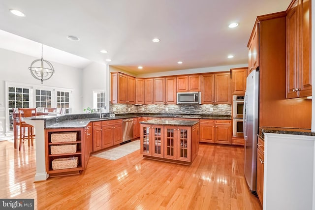 kitchen with a kitchen breakfast bar, stainless steel appliances, an inviting chandelier, a kitchen island, and hanging light fixtures