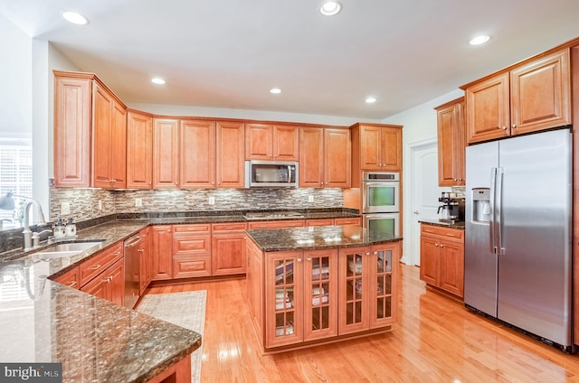 kitchen featuring a center island, dark stone counters, sink, light wood-type flooring, and stainless steel appliances