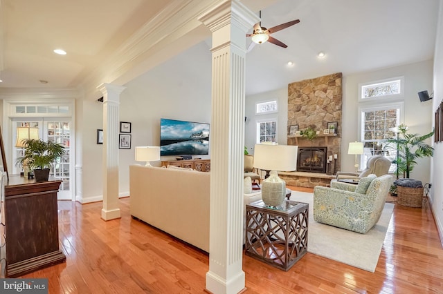 living room featuring a fireplace, decorative columns, a healthy amount of sunlight, and light hardwood / wood-style floors