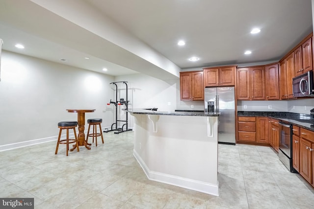 kitchen featuring a kitchen breakfast bar, a center island, stainless steel appliances, and dark stone counters