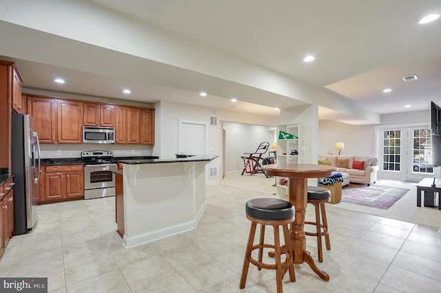 kitchen featuring a breakfast bar area, a kitchen island, light tile patterned floors, and appliances with stainless steel finishes