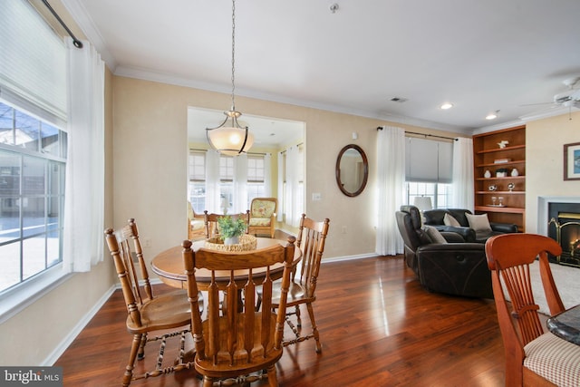 dining space featuring a healthy amount of sunlight, ornamental molding, and dark hardwood / wood-style flooring