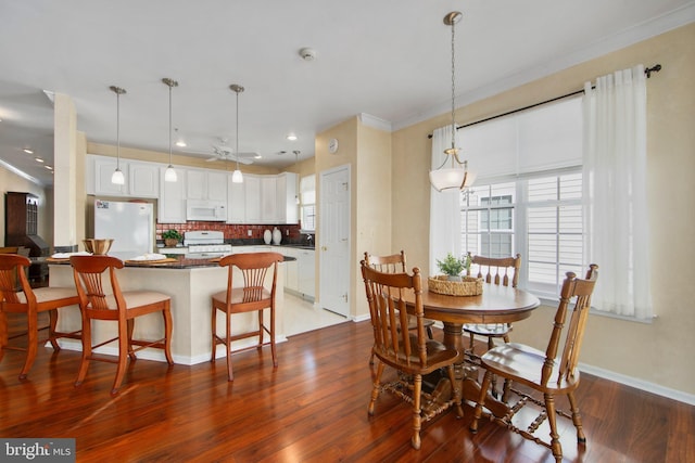 dining space featuring crown molding, hardwood / wood-style flooring, sink, and ceiling fan