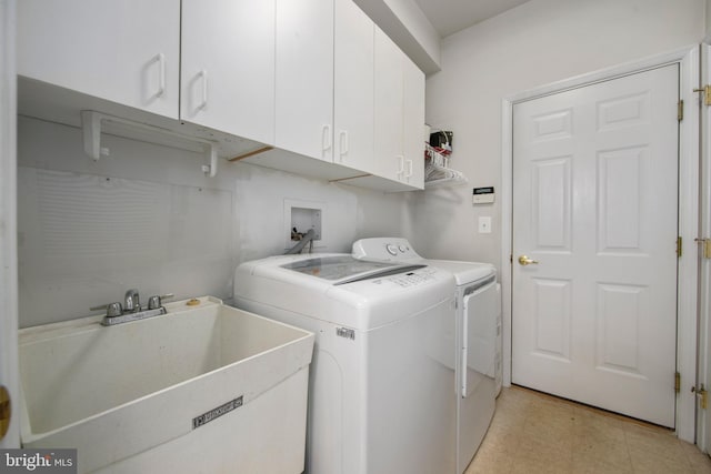 laundry room with sink, washing machine and dryer, and cabinets