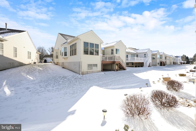 snow covered back of property featuring a wooden deck