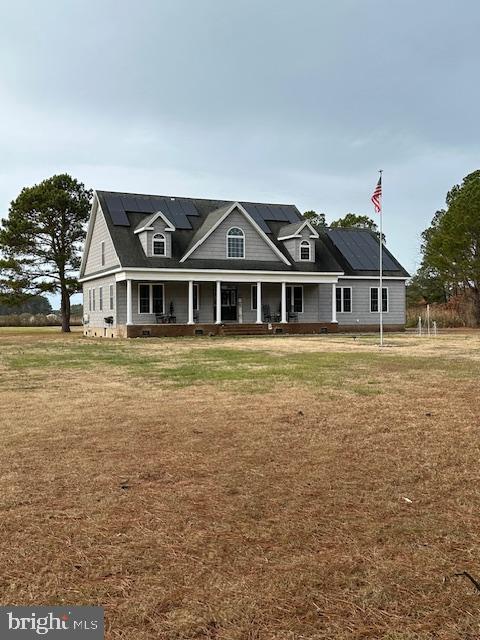 view of front of house with a front yard, solar panels, and covered porch