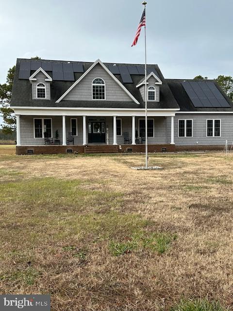 view of front of property featuring a front lawn, covered porch, and solar panels