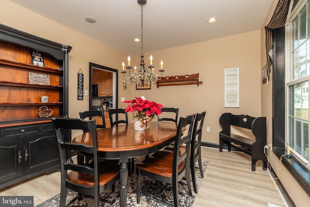 dining space with light wood-type flooring and an inviting chandelier