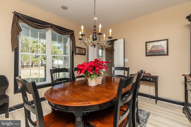 dining space with a healthy amount of sunlight, light hardwood / wood-style flooring, and a notable chandelier