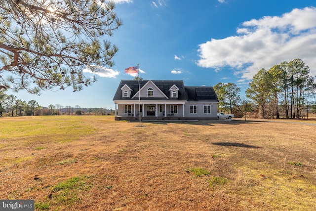 cape cod home featuring solar panels, covered porch, and a front yard