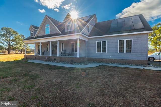 view of front of property featuring covered porch, solar panels, and a front yard