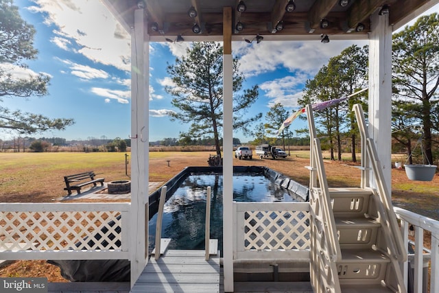 wooden deck with a rural view and an outdoor fire pit