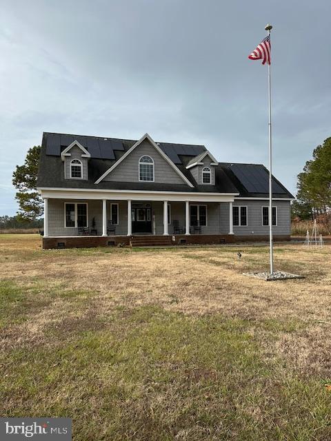 view of front of property with solar panels, covered porch, and a front yard