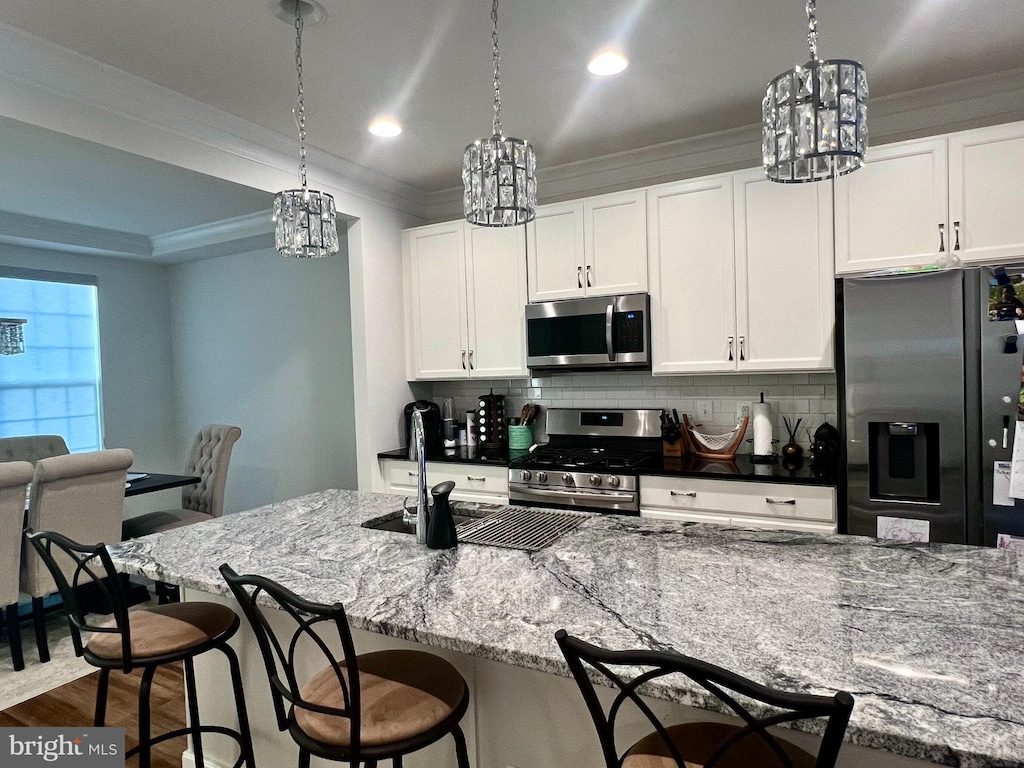 kitchen featuring stainless steel appliances, white cabinets, dark stone countertops, and tasteful backsplash