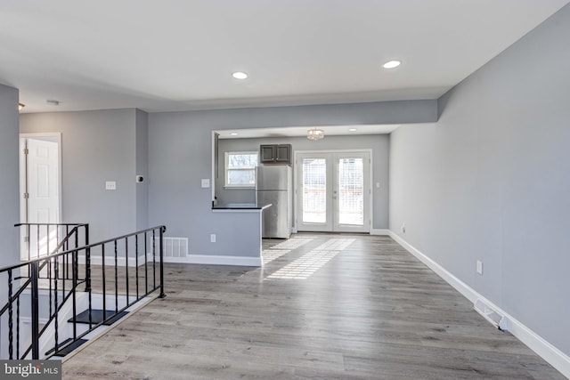 empty room featuring french doors and light hardwood / wood-style flooring