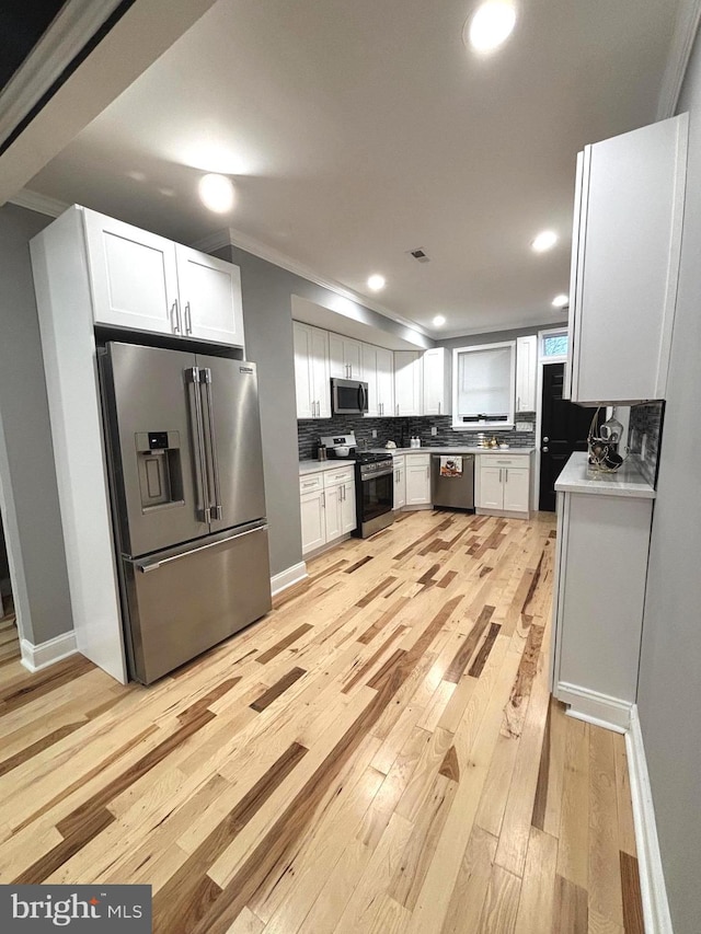 kitchen featuring light hardwood / wood-style floors, white cabinetry, appliances with stainless steel finishes, and tasteful backsplash