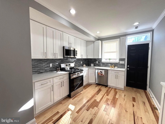 kitchen with backsplash, stainless steel appliances, and white cabinetry