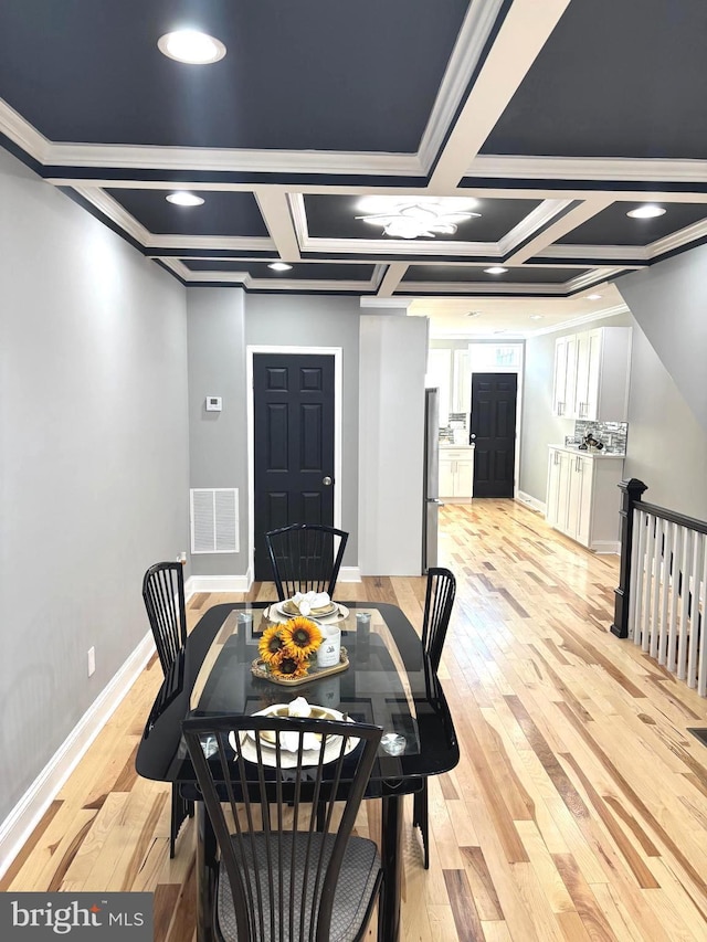 dining space featuring light hardwood / wood-style floors, ornamental molding, beam ceiling, and coffered ceiling