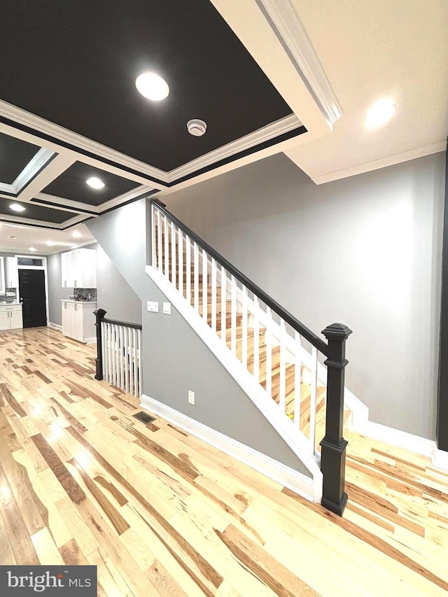 staircase featuring wood-type flooring and crown molding