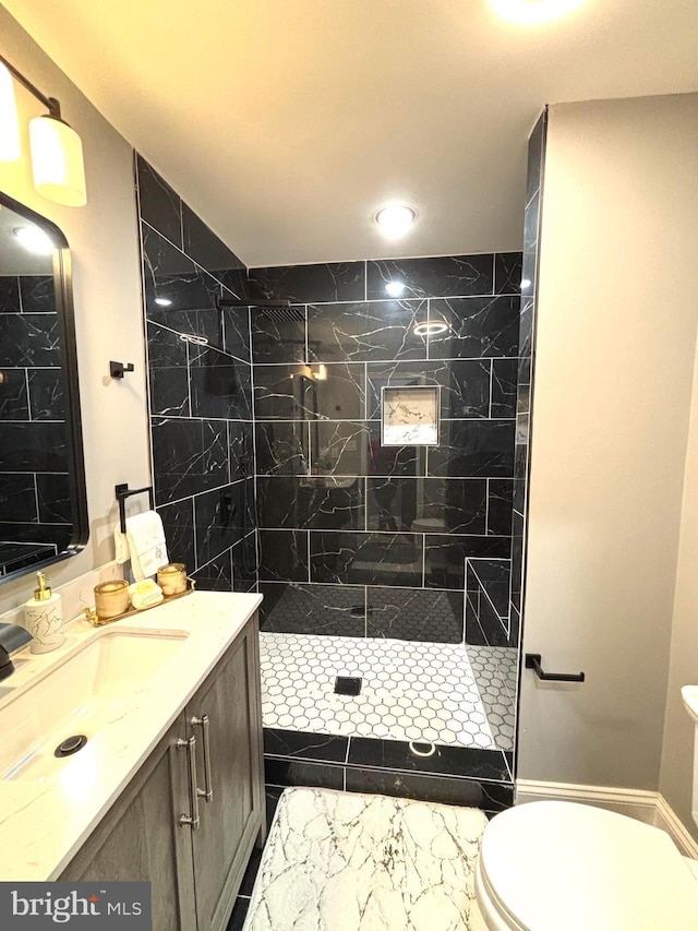 bathroom featuring vanity, toilet, and a tile shower