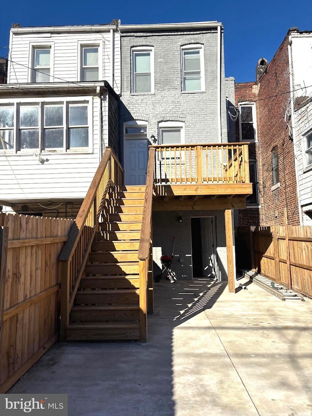 rear view of property featuring a wooden deck and a patio area