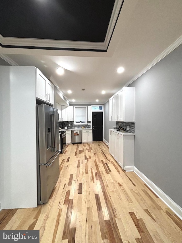 kitchen with tasteful backsplash, white cabinetry, and appliances with stainless steel finishes