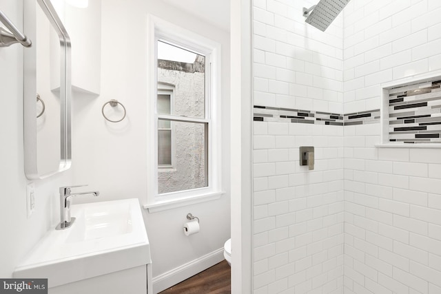 bathroom with vanity, toilet, wood-type flooring, and tiled shower