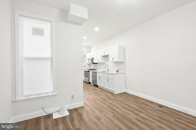 kitchen with white cabinetry, sink, light wood-type flooring, and appliances with stainless steel finishes