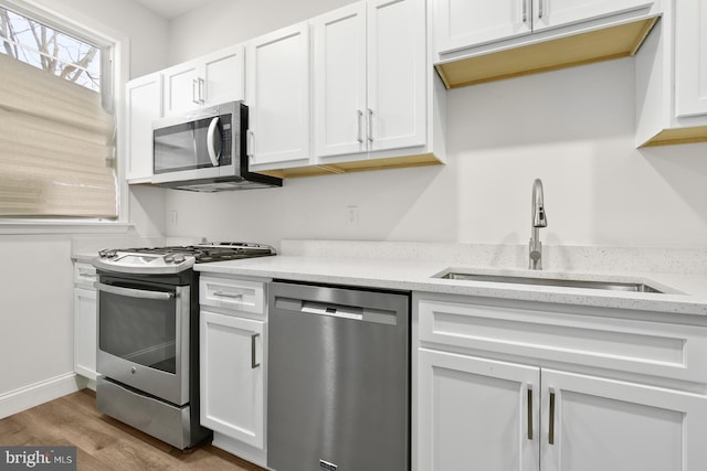 kitchen featuring sink, white cabinets, light hardwood / wood-style flooring, and appliances with stainless steel finishes