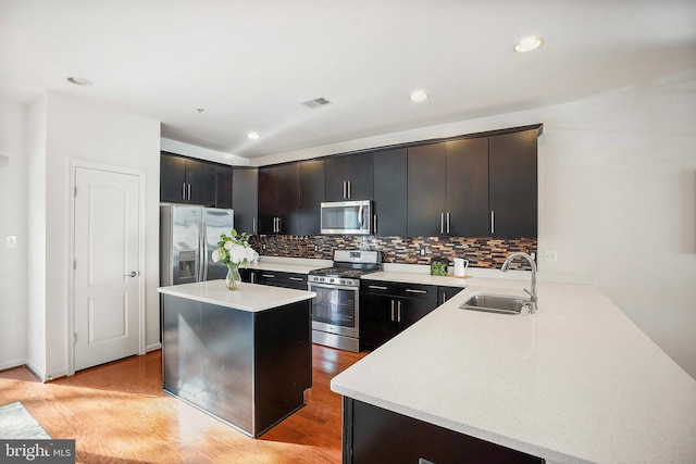 kitchen featuring kitchen peninsula, appliances with stainless steel finishes, sink, a center island, and light hardwood / wood-style floors