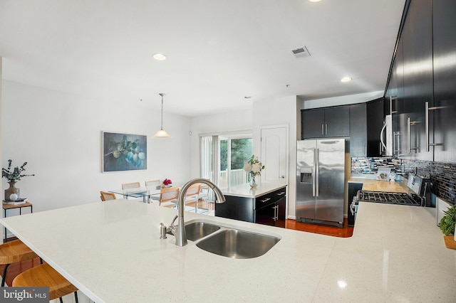 kitchen featuring decorative backsplash, a breakfast bar, stainless steel appliances, sink, and decorative light fixtures