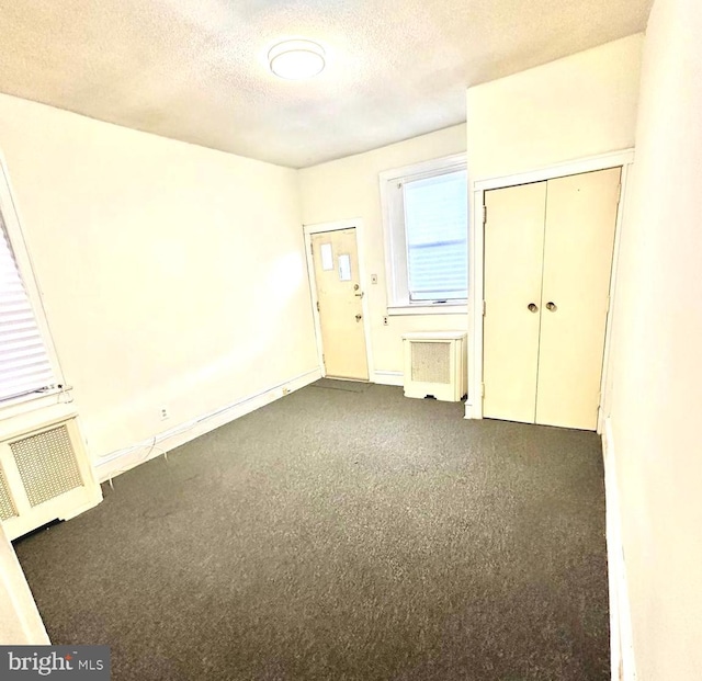 unfurnished bedroom with a textured ceiling, a closet, and radiator