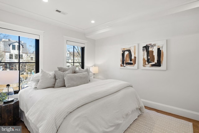 bedroom featuring recessed lighting, wood finished floors, visible vents, baseboards, and crown molding