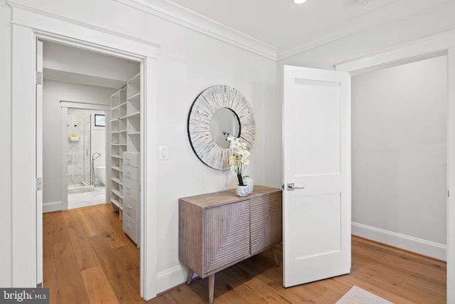 hall featuring baseboards, crown molding, and wood finished floors