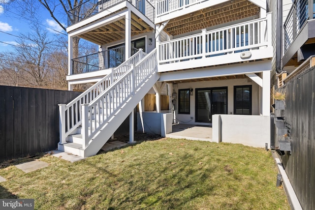 back of property with a patio area, a fenced backyard, a lawn, and stairway