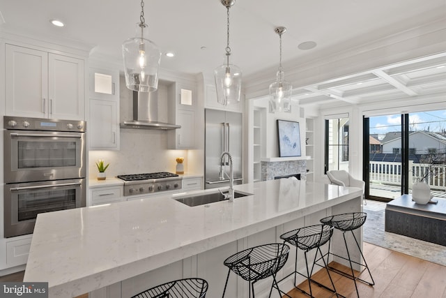 kitchen featuring stainless steel appliances, a sink, open floor plan, hanging light fixtures, and glass insert cabinets