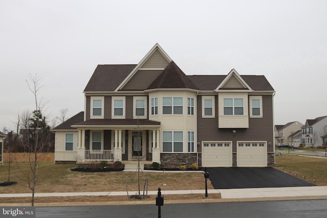 view of front of property with an attached garage, stone siding, covered porch, and driveway