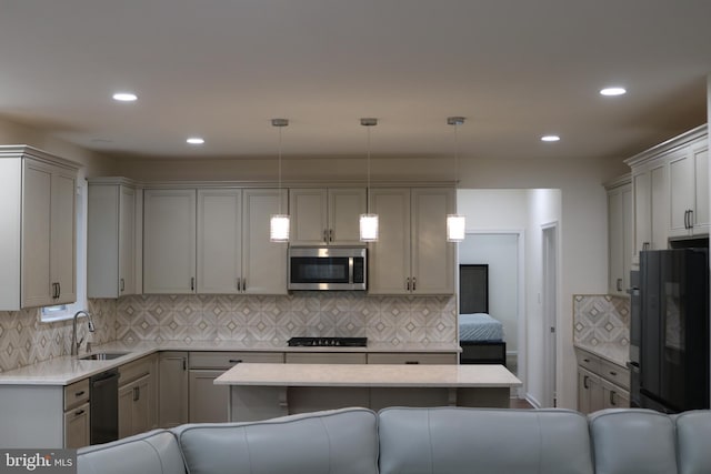 kitchen with gray cabinetry, sink, black appliances, hanging light fixtures, and a breakfast bar area