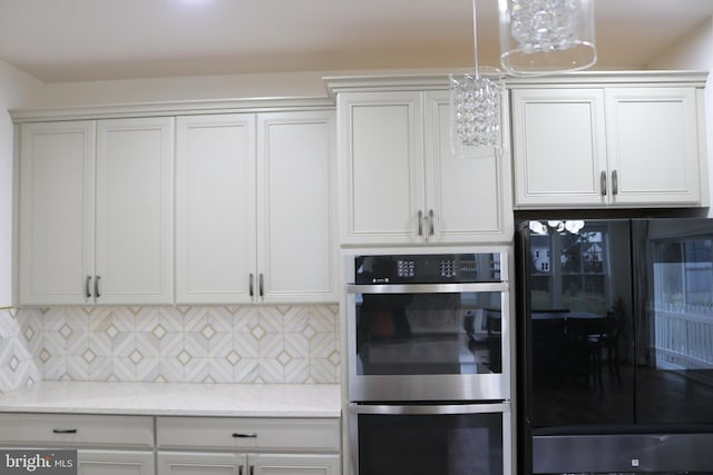 kitchen featuring white cabinets, black refrigerator, light stone countertops, double oven, and tasteful backsplash