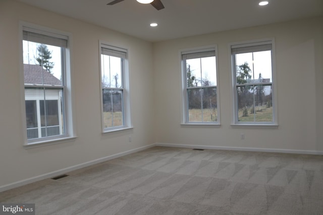 spare room with light carpet, a wealth of natural light, and ceiling fan