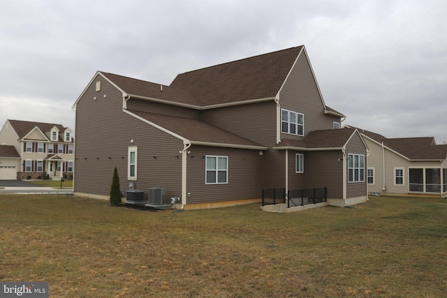 back of property featuring central air condition unit and a yard