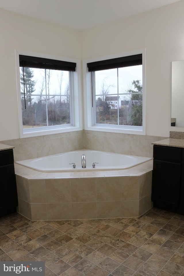 bathroom with vanity and a relaxing tiled tub