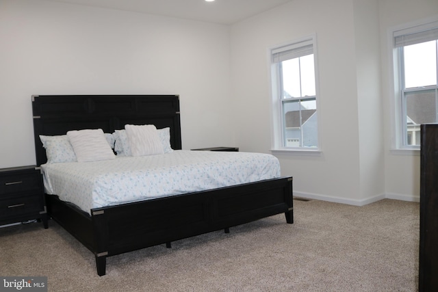 bedroom featuring light colored carpet and multiple windows