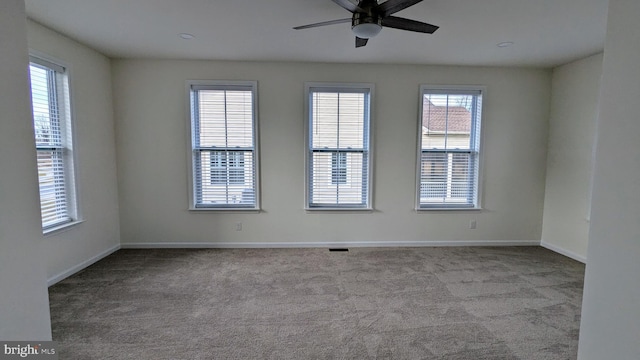 carpeted spare room featuring a wealth of natural light and ceiling fan