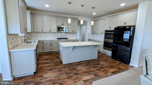 kitchen featuring sink, black appliances, a center island, dark hardwood / wood-style floors, and hanging light fixtures